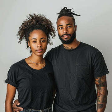 Two people wearing black t-shirts against a plain background
