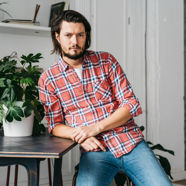 Man in a plaid shirt sitting in a room with plants and furniture